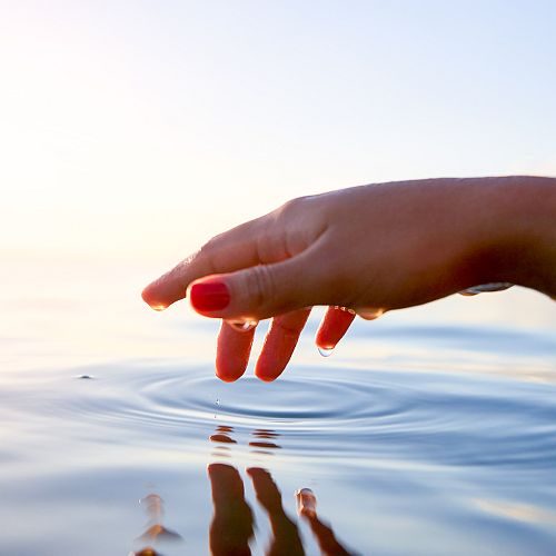 woman with her hand above water creating ripples of purpose